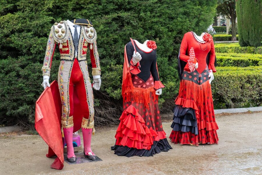 Traditional flamenco dresses and bullfighting suit displayed outdoors in Madrid