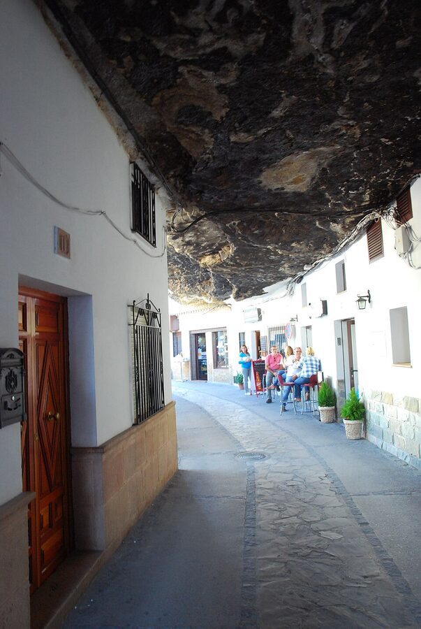 A street in Setenil de las Bodegas with whitewashed houses and rock above