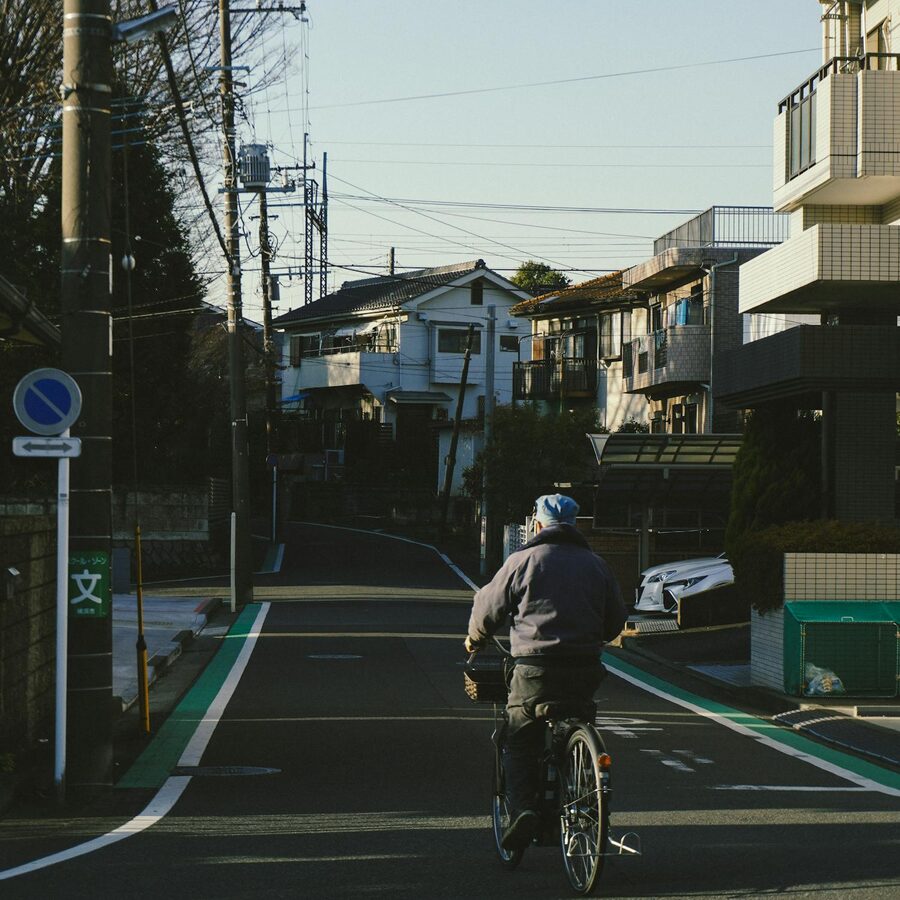 Senior man riding a bicycle through a quiet residential street in Tokyo