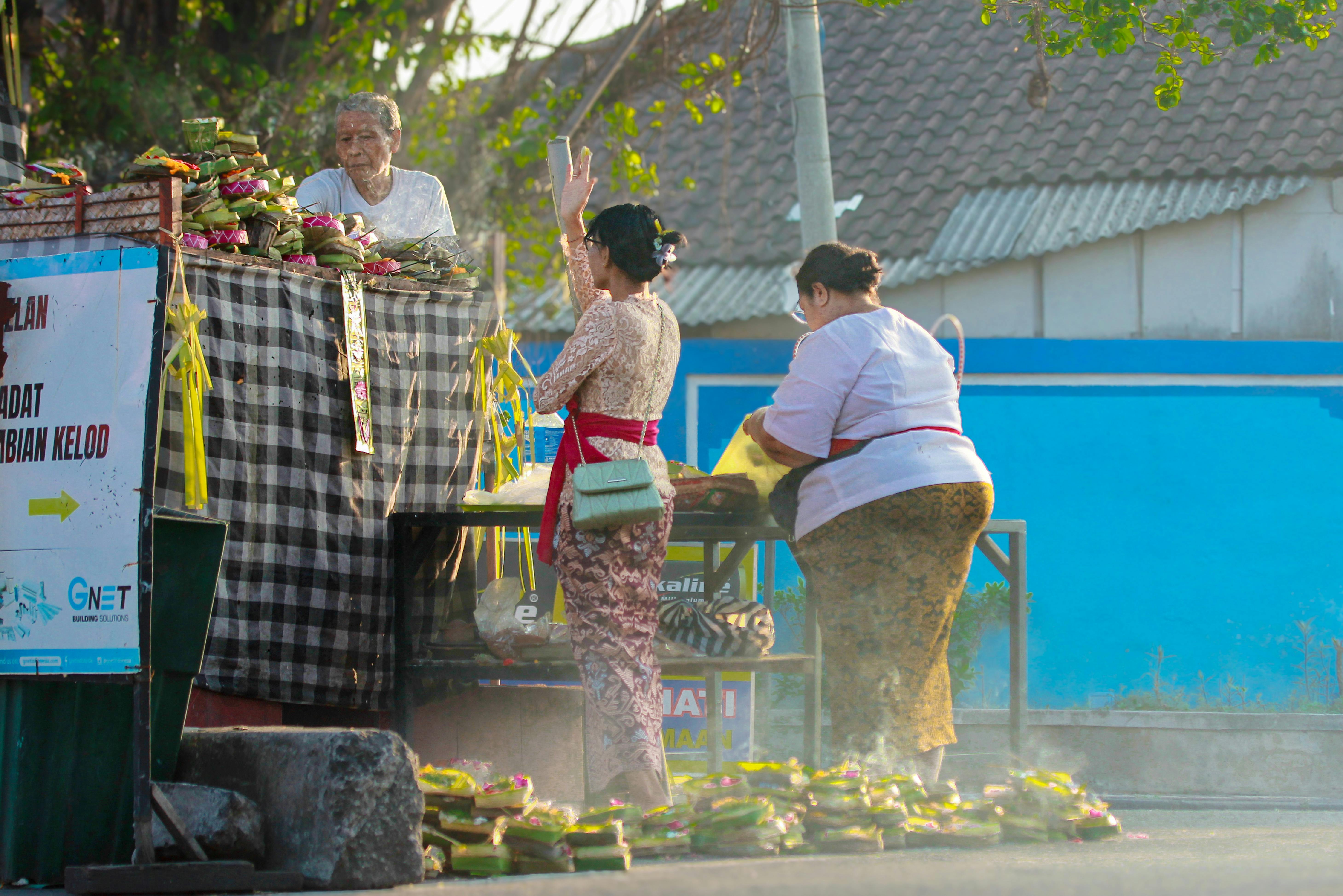 Balinese women in traditional attire preparing temple offerings