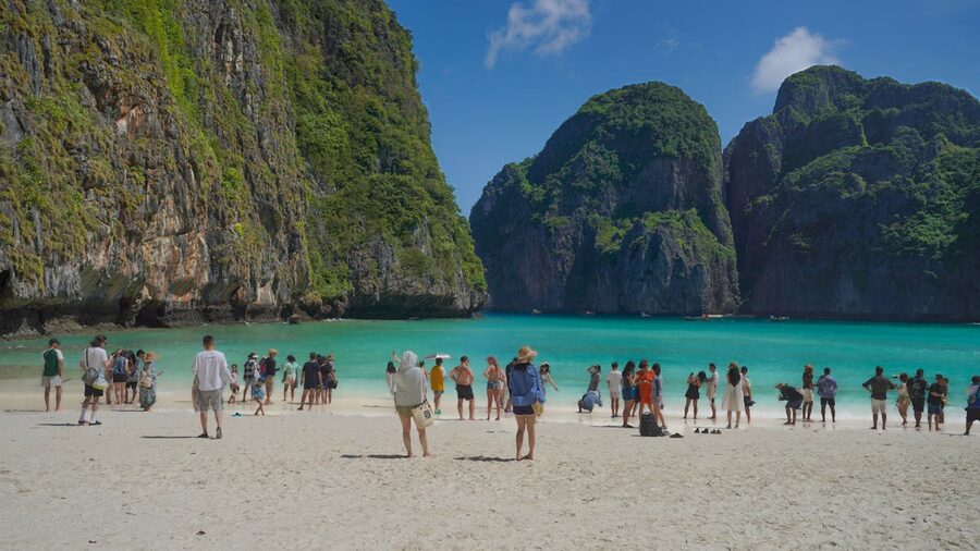 Visitors walking on the beach at Maya Bay surrounded by limestone cliffs