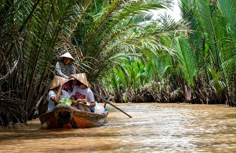 Traditional boat gliding through palm-lined waterways in the Mekong Delta
