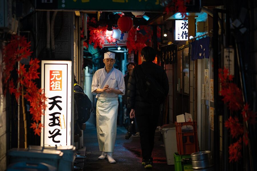 Chef walking through Memory Lane narrow street in Shinjuku at night