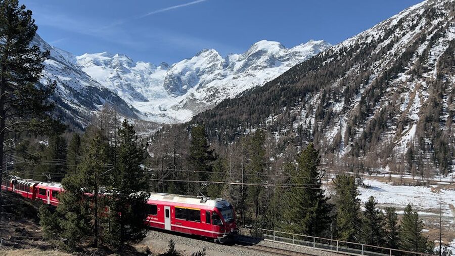 Bernina Express red train against snowy Swiss Alps peaks