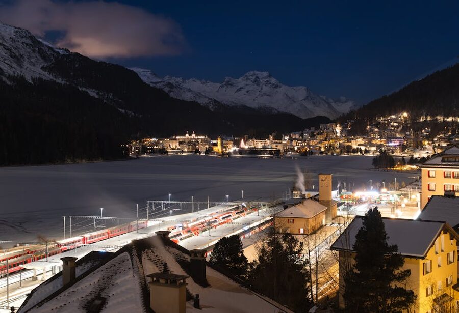 St Moritz train station illuminated at night with snowy mountains