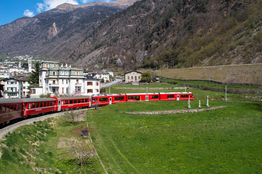 Bernina Express train passing village in Swiss Alps mountains