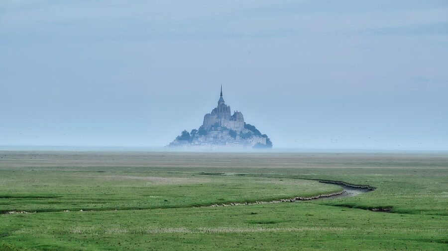 Mont Saint Michel in morning fog rising above the bay
