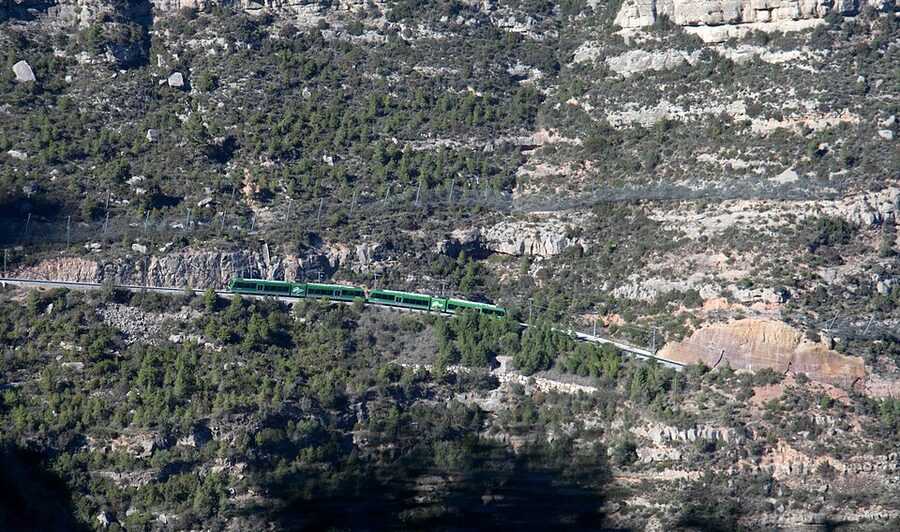 Yellow cremallera rack railway train climbing toward Montserrat monastery
