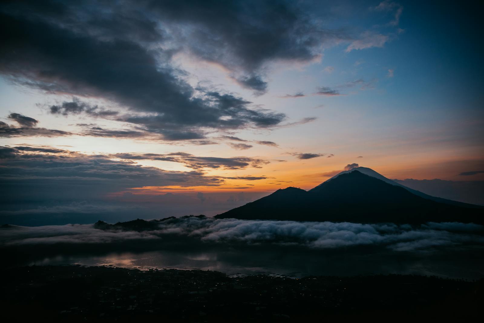 Dramatic sunrise with orange and purple sky behind the silhouette of Mount Batur