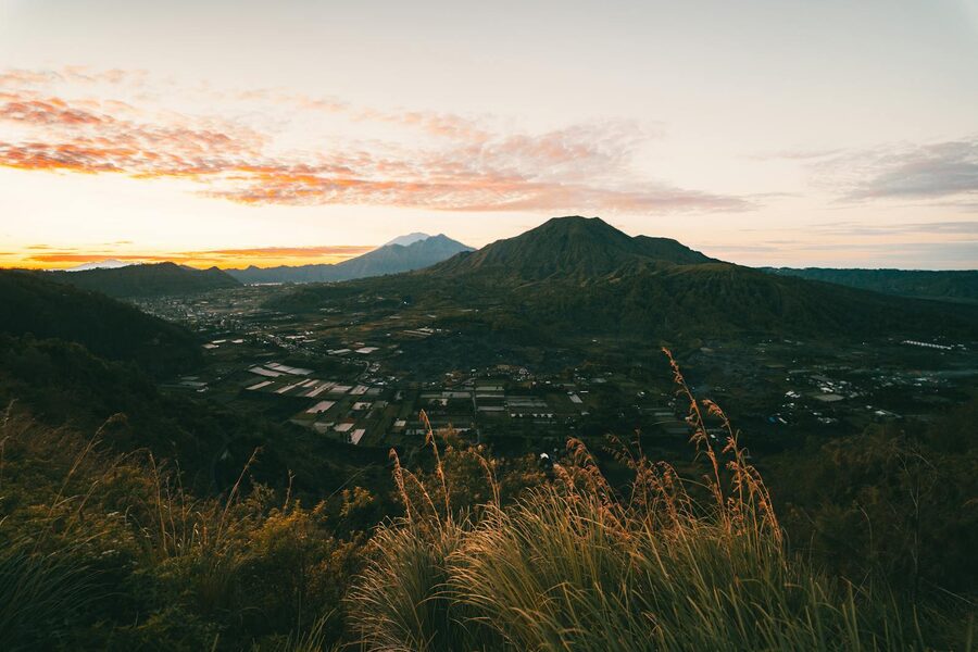 View of Lake Batur from the summit of Mount Batur at sunrise with volcanic peaks in the distance