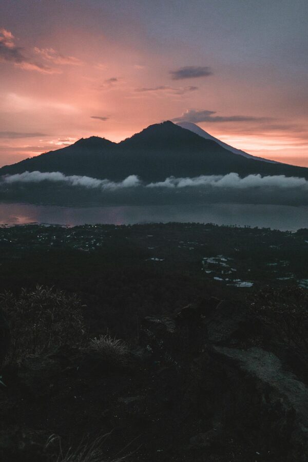 Hikers watching an orange and pink sunrise from the summit of Mount Batur in Bali