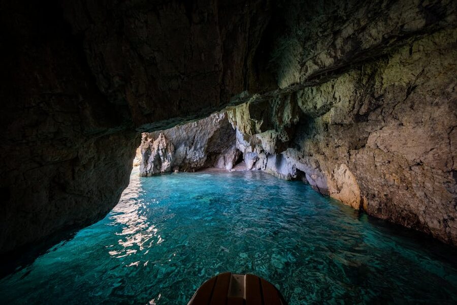 A small boat inside a sea cave with bright turquoise water near Capri