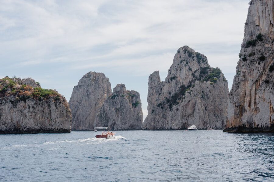 A small boat sailing past the dramatic limestone cliffs of Capri