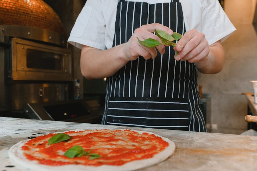 Adding fresh basil to a pizza