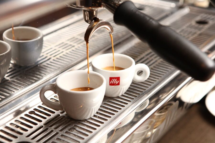 Espresso pouring into ceramic cups from coffee machine