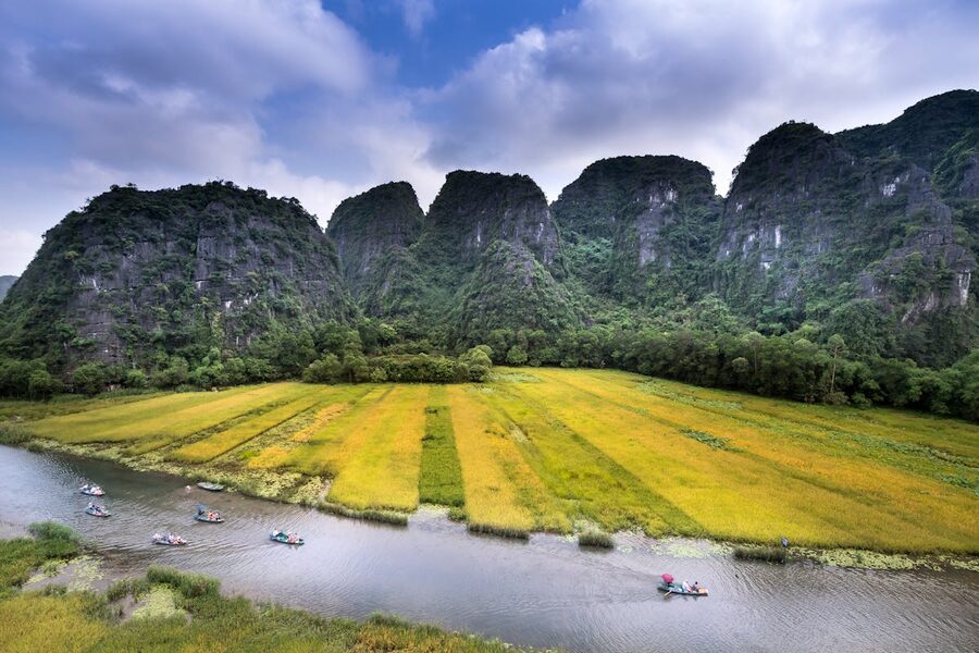 Boats floating on a river lined with towering limestone karsts in Ninh Binh Vietnam