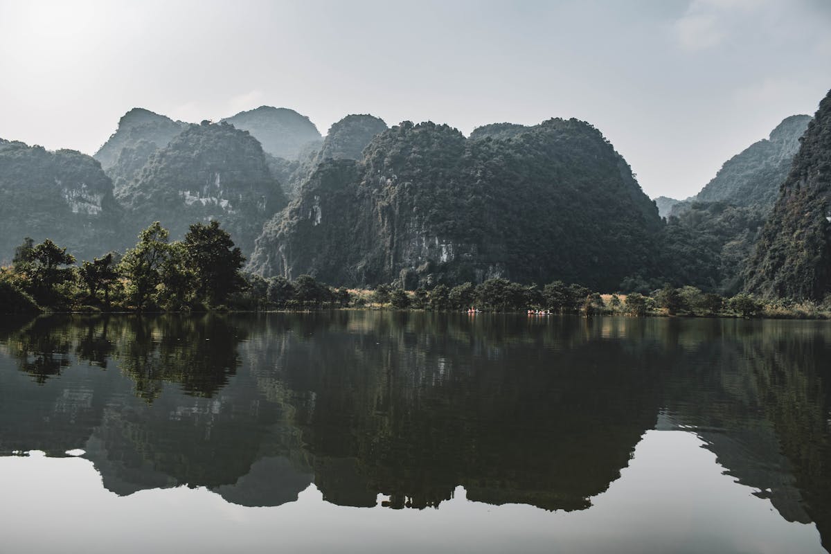 Peaceful reflection of limestone mountains in tranquil water in Ninh Binh Vietnam