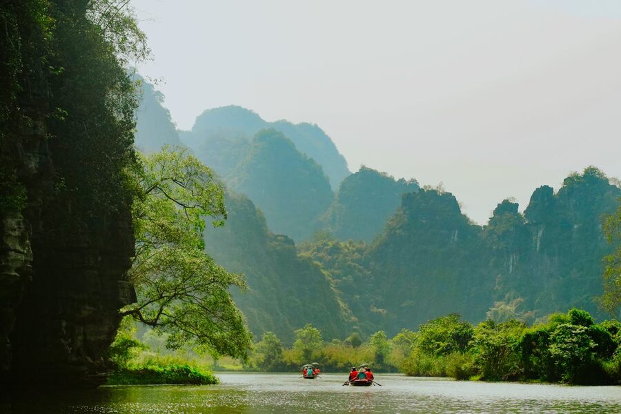 Peaceful river scene with travellers boating past limestone karsts in Hoa Lu Ninh Binh Vietnam