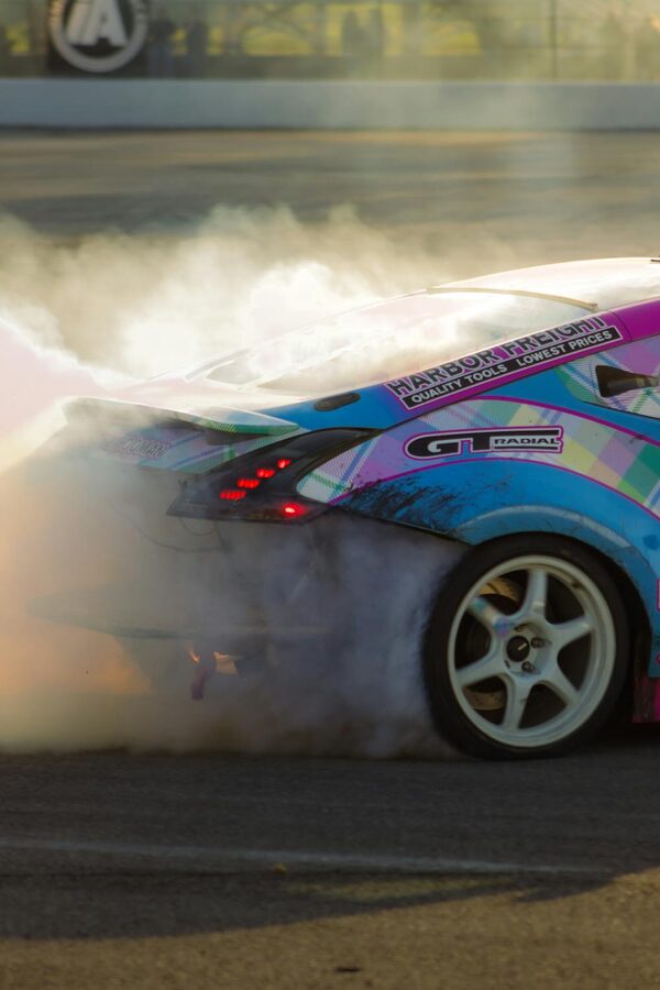 Nissan 370Z drifting on a racetrack enveloped in tire smoke