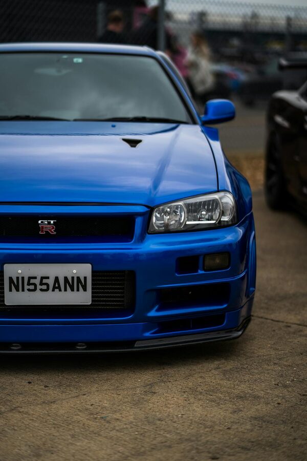 Close-up of a blue Nissan GT-R R34 at an outdoor car show