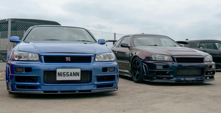 Two Nissan GTR R34 sports cars displayed side by side at an outdoor event
