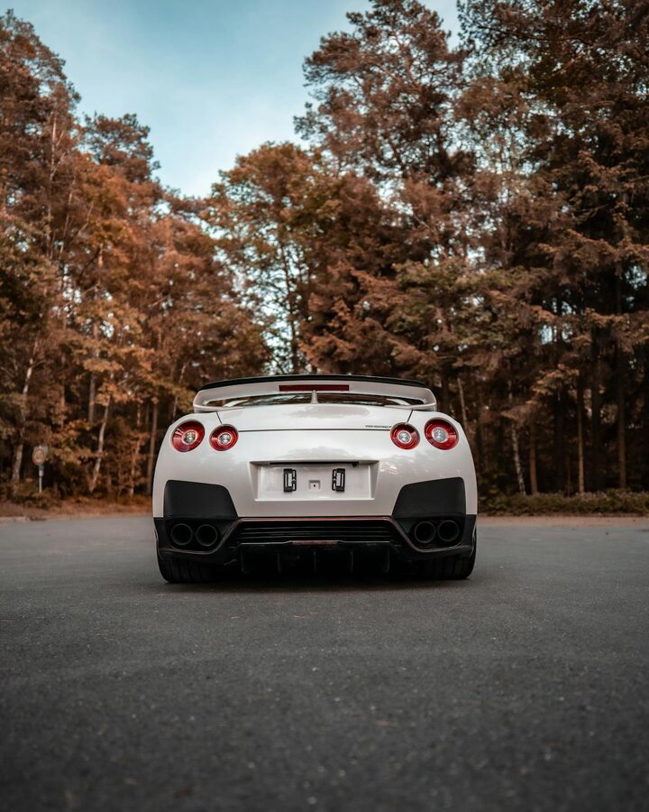 Rear view of a Nissan GTR parked on a road surrounded by autumn trees