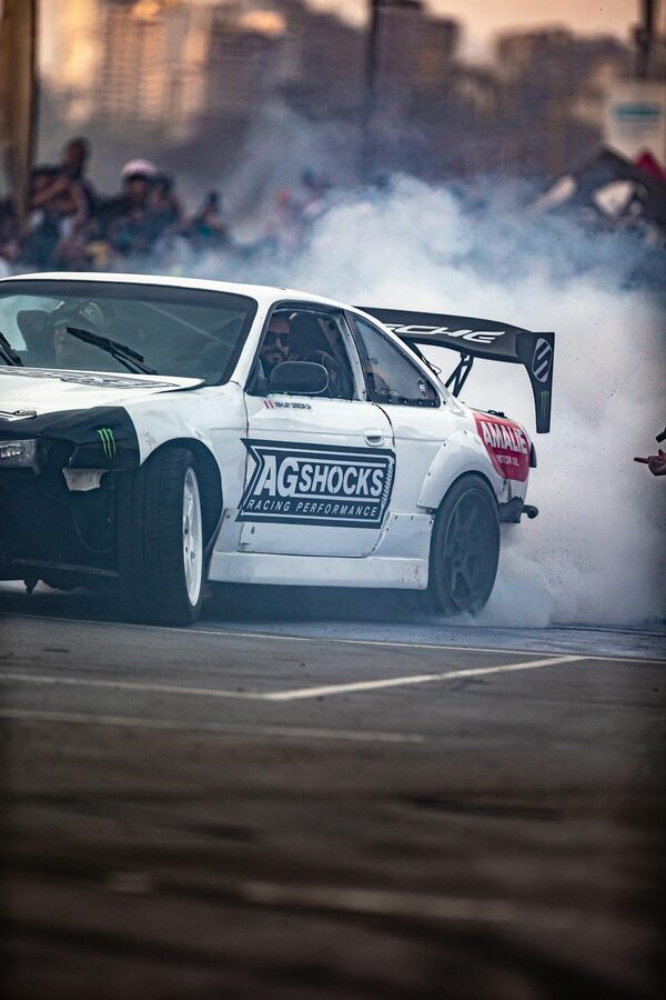 Nissan Silvia with white racing livery performing a drift on a racetrack