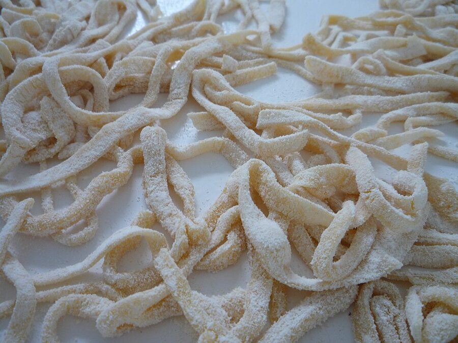 Cutting fresh tagliatelle by hand on a wooden board