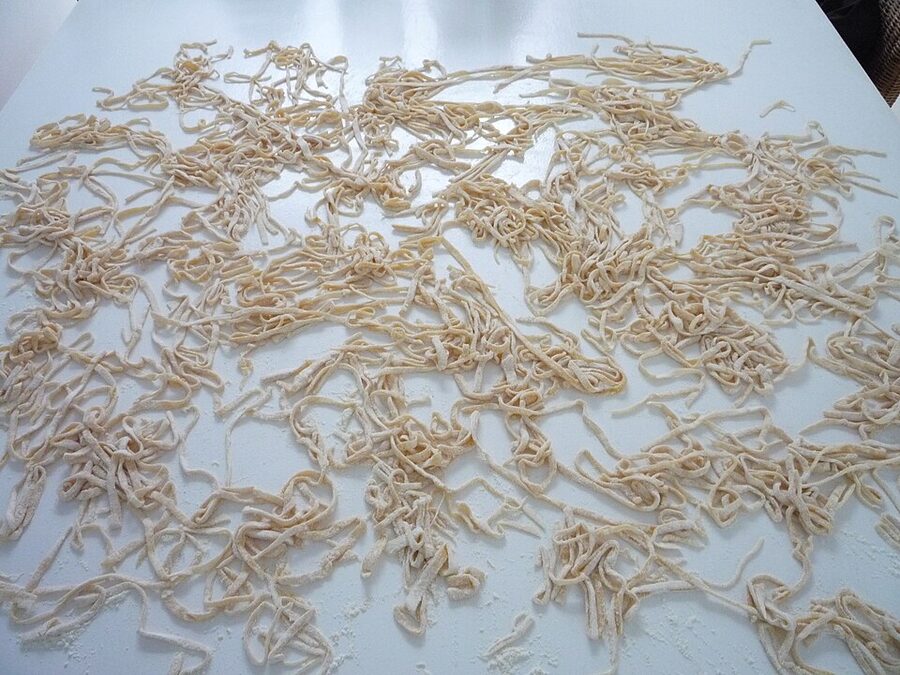 Nonna rolling fresh tagliatelle by hand in a home kitchen