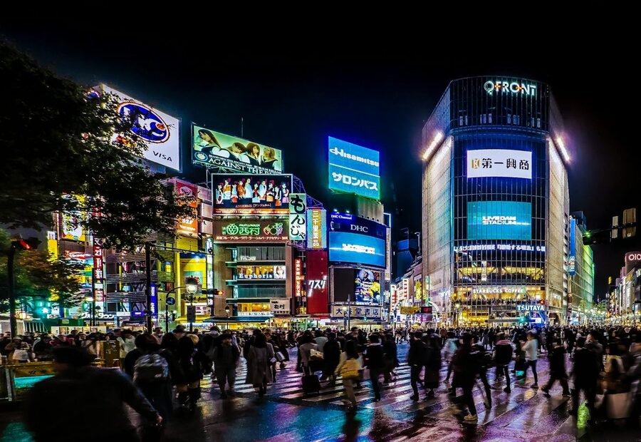 Busy Shibuya scramble crossing lit up with neon signs at night in Tokyo