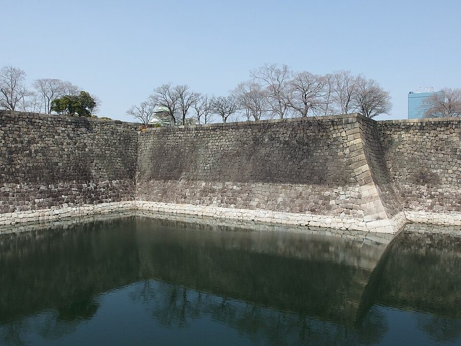 Stone-walled moat at Osaka Castle with high stone walls and water