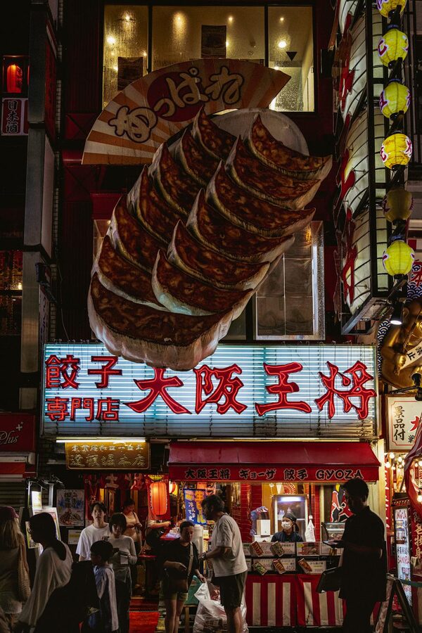 Lively night scene outside a gyoza restaurant on an Osaka street