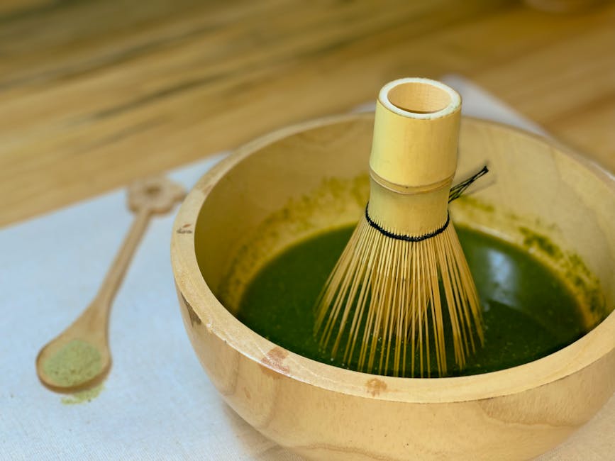 Matcha tea in wooden bowl with bamboo whisk