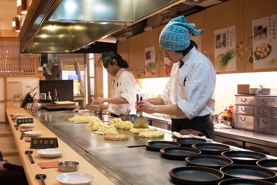 Chef preparing okonomiyaki on teppan in Osaka