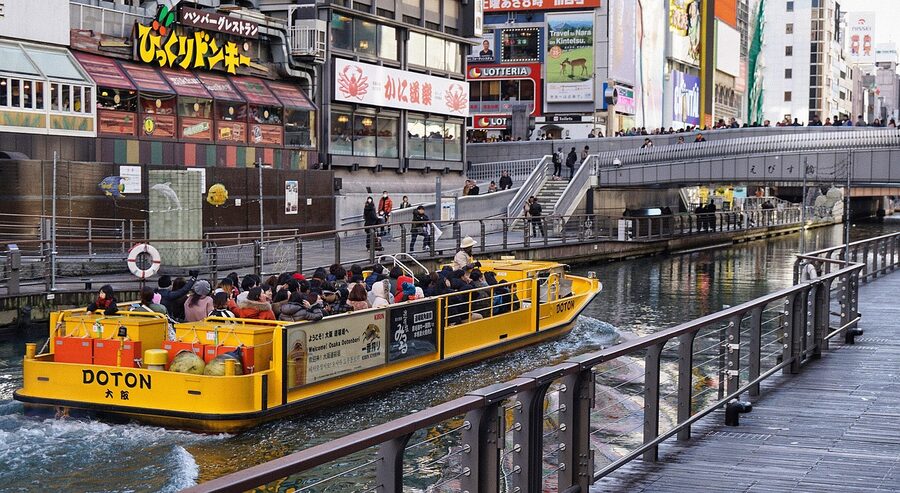 Dotonbori canal Osaka with sightseeing boat passing under a bridge