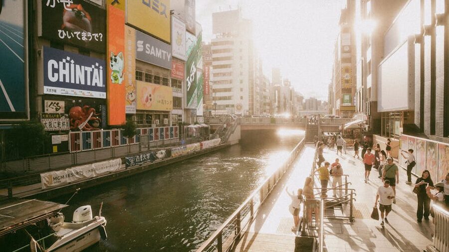 People walking along Dotonbori canal Osaka at sunset with neon signs