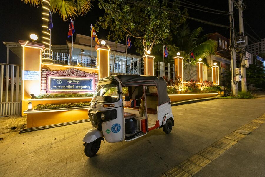 Tuk-tuk parked in front of a lit building at night in Cambodia