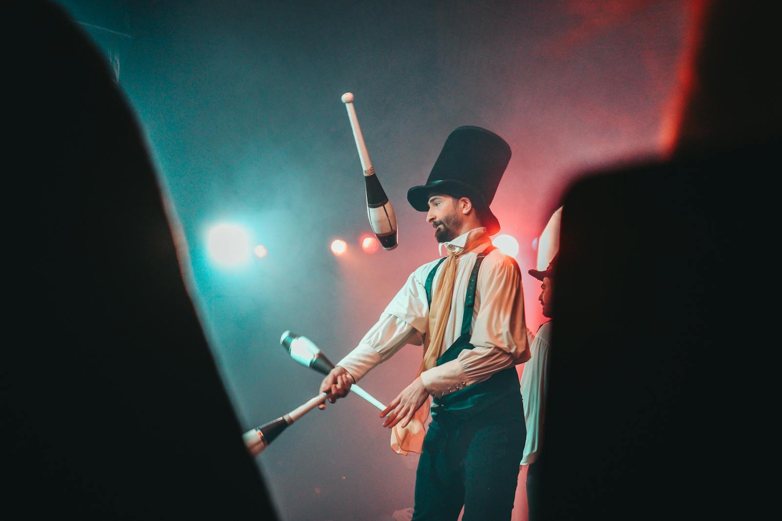 Juggler in a top hat performing under colored stage lights