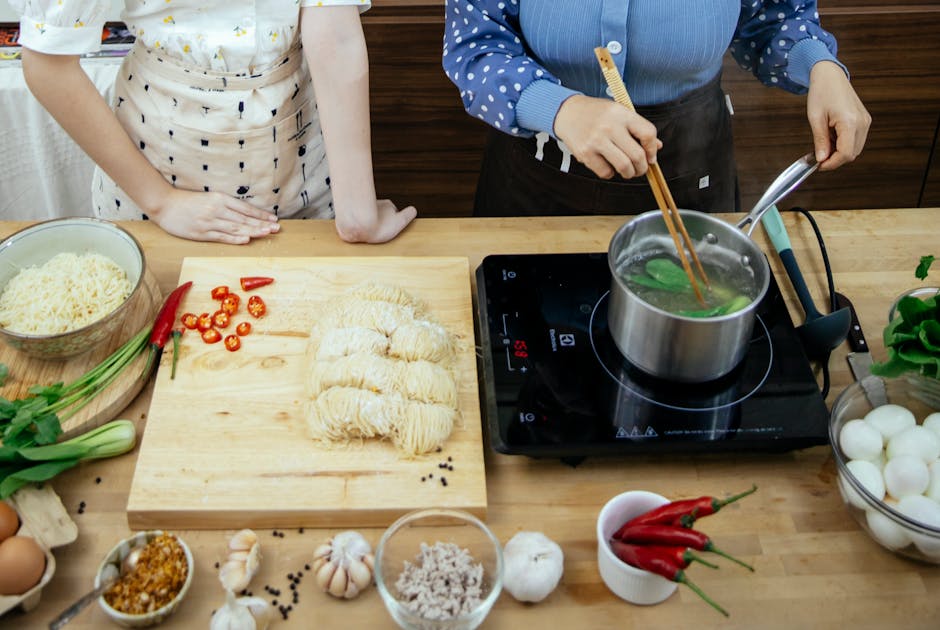 Women cooking greens in saucepans in a kitchen
