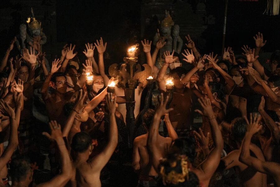 Balinese men performing Kecak dance with raised arms