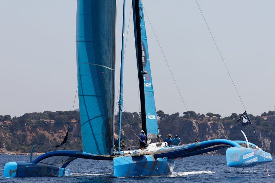 Catamaran sailing along rocky Mediterranean coastline