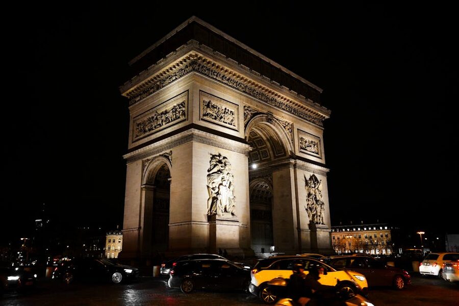 Arc de Triomphe lit up at night with traffic streaming around it