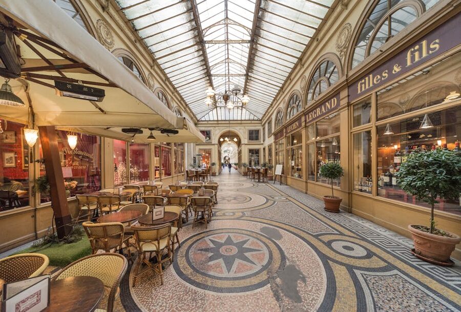 Restaurant tables in covered Paris passage with ornate architecture