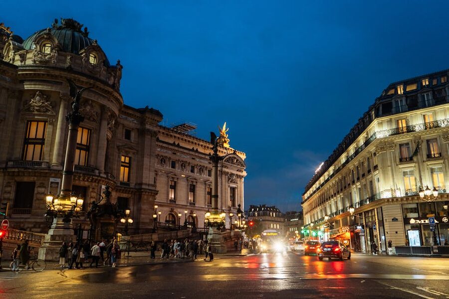 Palais Garnier illuminated at night against Paris traffic