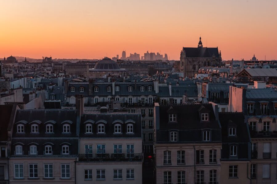 Paris rooftops at sunset under an orange sky