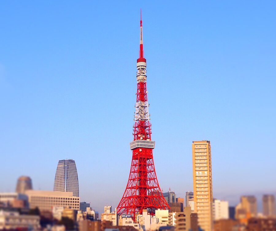 Tokyo Tower steel structure photographed from below against a clear blue sky with clouds