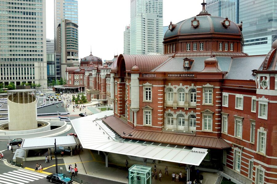 Historic red brick facade of Tokyo Station building with buses and vehicles in front