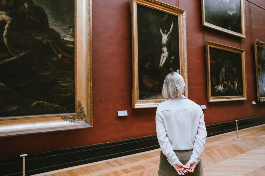 Visitor in art museum studying paintings
