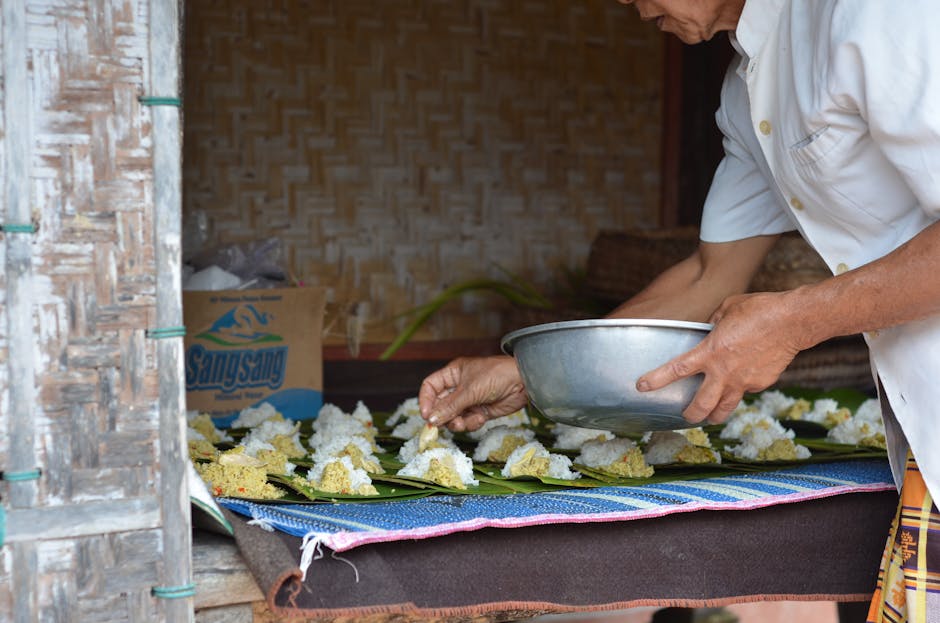 Person preparing rice offerings on banana leaves in Bali