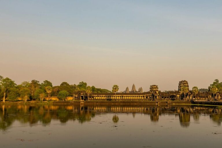 Angkor Wat temple reflecting in calm waters at sunrise